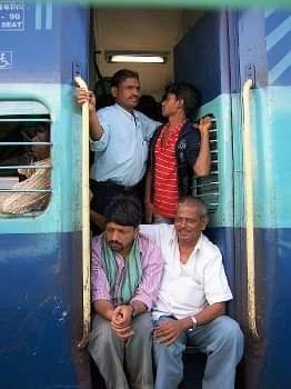 Indien Zugreisen: alles Wissenswerte von der Buchung über Zugklassen bis zur Reise MANU SARONA • health mind spirit • Dein Blog für ganzheitliches Wohlbefinden Gruppe Inder, die aus der Tür eines indischen Zugs gucken